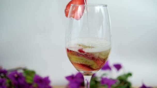 Aardbei en kiwi plakjes in wijnglas met witte achtergrond — Stockvideo