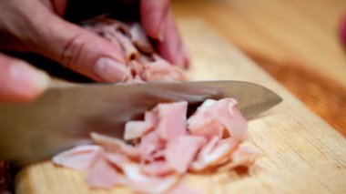 Kesme tahtasında taze hindi eti dilimleyen eller.