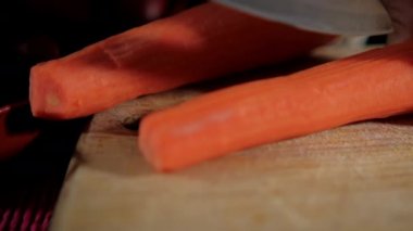 Kesme tahtasının üzerinde soyulmuş patates ve havuç dilimleyen eller.