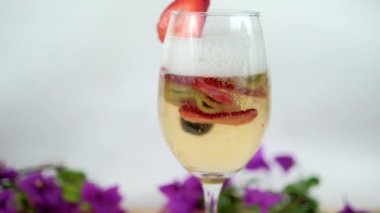 Beyaz arkaplanlı şarap kadehinde çilek ve kivi dilimleri.