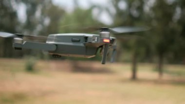 Arka planda bulanık ağaçlarla alçaktan uçan dron