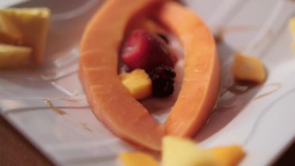 Méz öntése friss gyümölcsszeletekre porcelán lemez felett — Stock videók