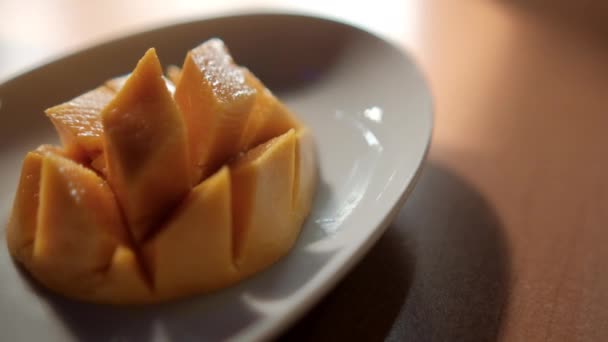 Mango cortado en cubitos en plato blanco sobre mesa marrón — Vídeo de stock