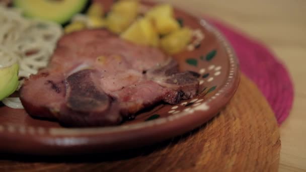 Schweinekotelett und weiße Spaghetti auf traditionellem Tonteller — Stockvideo