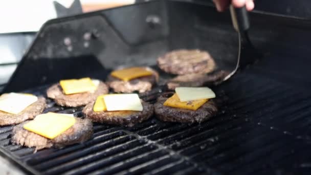 Mano con spatola muovendo carne hamburger con formaggio sopra griglia — Video Stock