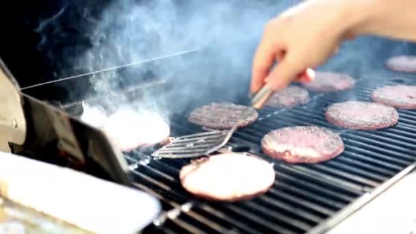 Чоловіча рука перевертає сире м'ясо гамбургерів на грилі з залізного барбекю — стокове відео