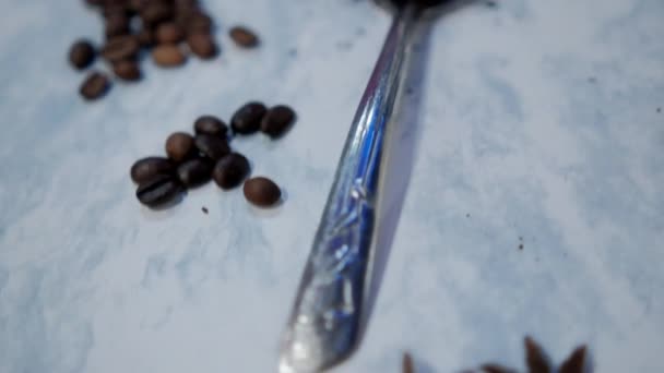 Lžíce kávy obklopená hromady kávových zrn na bílém povrchu — Stock video