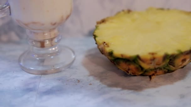 Ízletes vanília tejturmix és ananász szelet felett fehér márvány háttér — Stock videók