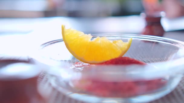 Orangenscheibe und Chilipulver auf Glasplatte oben auf grauer Tischmatte — Stockvideo