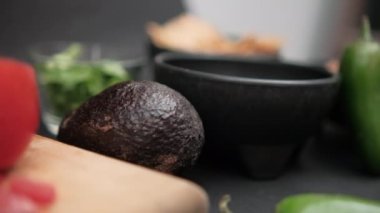 Kâseler, kırmızı biber, avokado ve dilimlenmiş domates ve siyah arkaplanlı soğan.