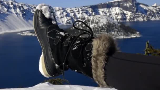 Kvinna fot i snö boot med snöiga berg och sjö som bakgrund — Stockvideo