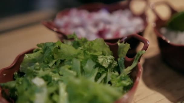 Macetas de arcilla de rábanos picados, cebollas, lechuga y limas sobre una mesa de madera — Vídeos de Stock