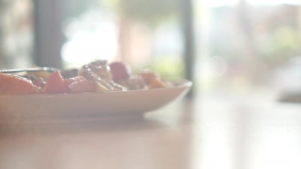 Тарелка нарезанных фруктов со сливками, овсянкой и вилкой сверху — стоковое видео