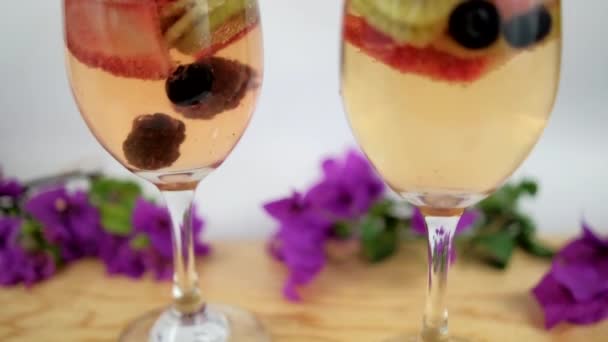 Bebidas con rodajas de fresa y kiwi en copas de vino con fondo blanco — Vídeo de stock