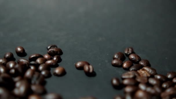 Куча жареных кофейных зерен на черной поверхности — стоковое видео