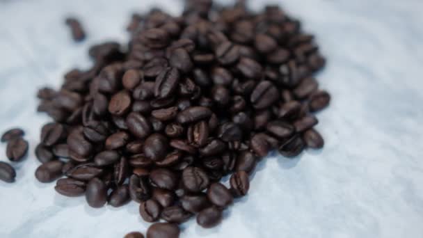 O grămadă mică de boabe de cafea prăjite pe suprafața albă — Videoclip de stoc