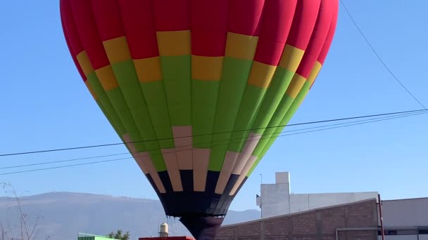 Mavi gökyüzünün altında renkli bir sıcak hava balonunu ısıtıp şişiriyor. — Stok video