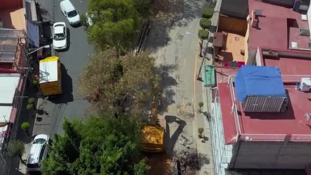 Vista aérea de una excavadora excavando en el sitio de construcción bajo los árboles — Vídeos de Stock