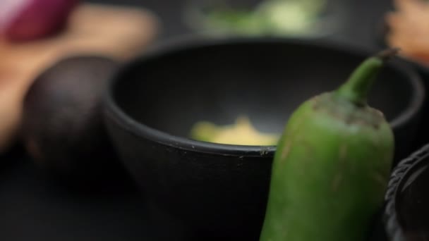 Pimentos e tigelas de abacate picado e feijão frito na superfície preta — Vídeo de Stock