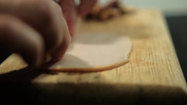 Hands rolling turkey ham slices above cutting board — Stock Video