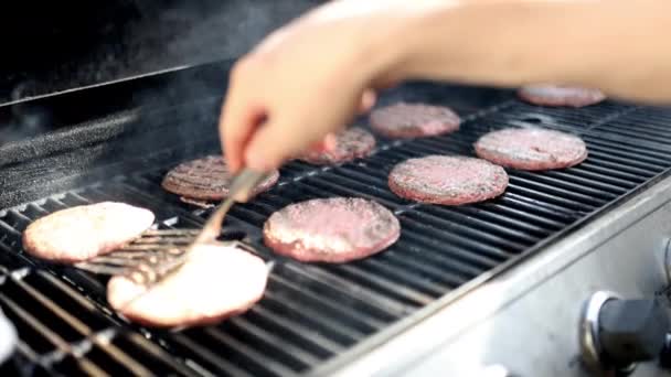 Αρσενικό χέρι flipping ωμό κρέας χάμπουργκερ στο μπάρμπεκιου σιδήρου — Αρχείο Βίντεο