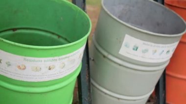 Parktaki renkli çöp kutularının üzerinde İspanyolca işaretler var