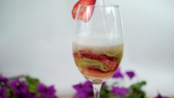 Aardbei en kiwi plakjes in wijnglas met witte achtergrond — Stockvideo