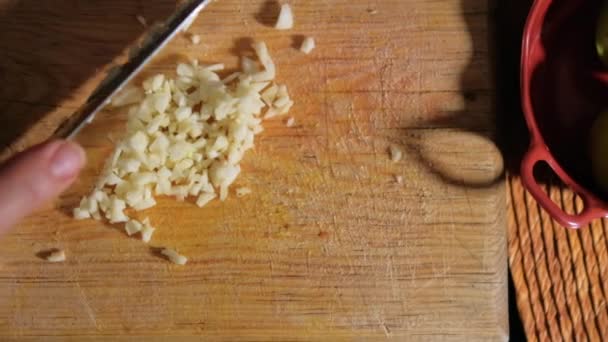 Mani che tagliano spicchi d'aglio su un tagliere di legno — Video Stock