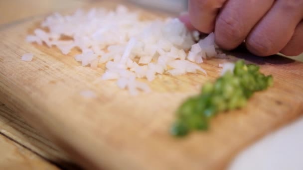 Hands slicing onion and green chili peppers on a cutting board — Stock Video