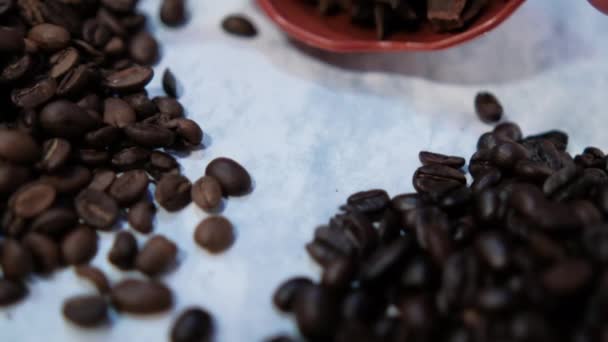 Маленькие стопки кофейных зерен и семена аниса на белой поверхности — стоковое видео