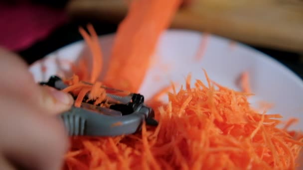 Manos pelando zanahoria fina con pelador de juliana sobre plato blanco — Vídeos de Stock