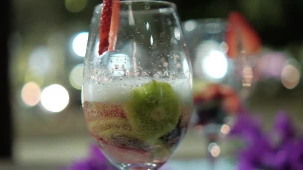 Bevanda con fette di frutta in bicchiere di vino con sfondo sfocato — Video Stock