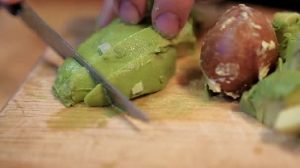 Handen langzaam snijden van een avocado op snijplank — Stockvideo