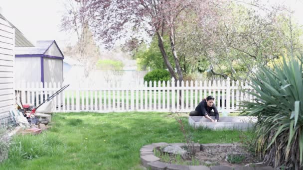 Brunette femme cachant des œufs de Pâques dans le jardinier dans le jardin — Video