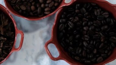 Üç kap kavrulmuş kahve çekirdeği ve beyaz yüzeyde yıldız anason tohumları.
