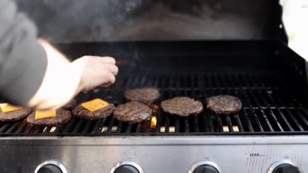 Mangal ızgarasının üstündeki hamburger etinin üstüne peynir dilimleri koyuyorsun. — Stok video