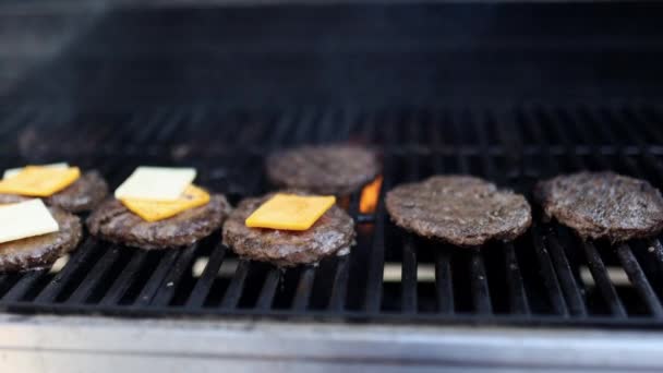Hand med spatel flyttar hamburgare kött med ost ovanför grill — Stockvideo