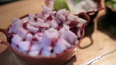 Ahşap masada doğranmış turp, soğan, marul ve limon saksıları.