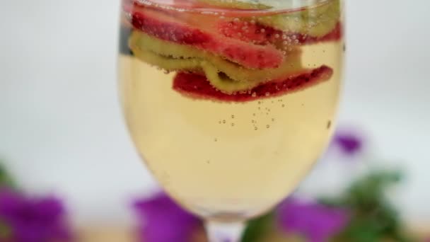 Eper és kivi italban lebegő szeletei borospohárban — Stock videók