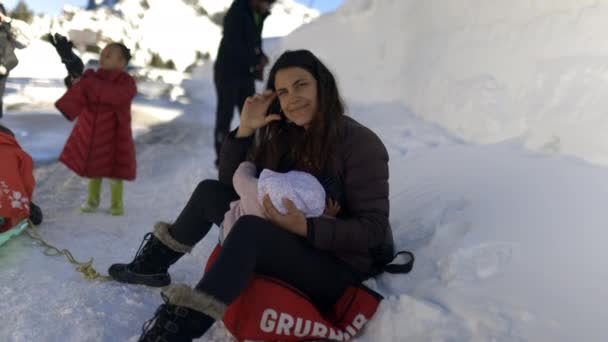 Jong moeder omringd door sneeuw mounds borstvoeding haar baby — Stockvideo