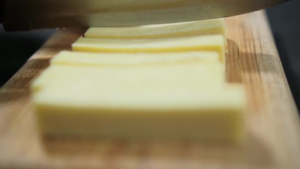 Handen snijden verse Manchego kaas op een snijplank — Stockvideo