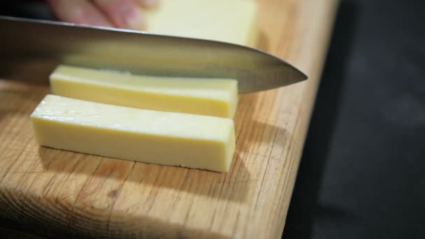 Kesme tahtasında taze Manchego peyniri dilimleyen eller. — Stok video