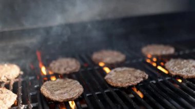 Demir ızgaranın üstünde hamburger eti var.