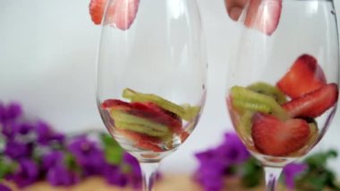 Beyaz arkaplanlı şarap kadehlerinde çilek ve kivi dilimleri