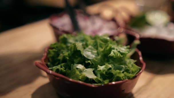 Tontöpfe mit gehackten Radieschen, Zwiebeln, Salat und Limetten auf Holztisch — Stockvideo