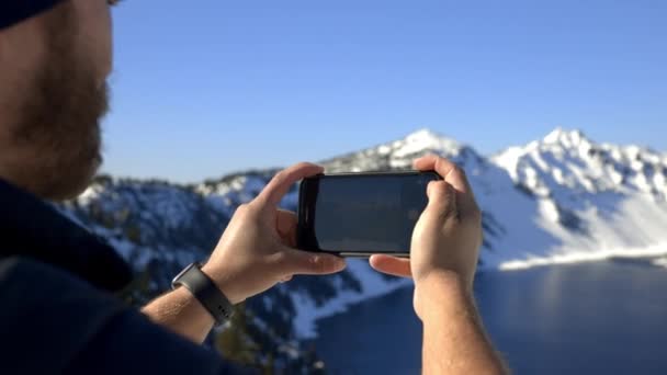 Людина фотографує красивий сніжний гірський хребет і озеро — стокове відео