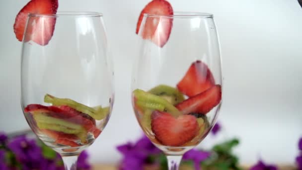 Fette di fragola e kiwi in bicchieri di vino con sfondo bianco — Video Stock
