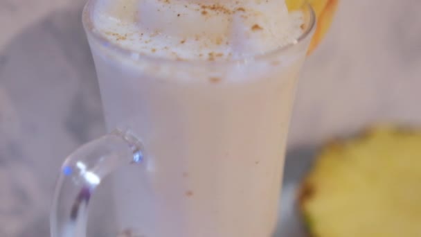 Lekkere vanille milkshake en ananas plak boven witte marmeren achtergrond — Stockvideo