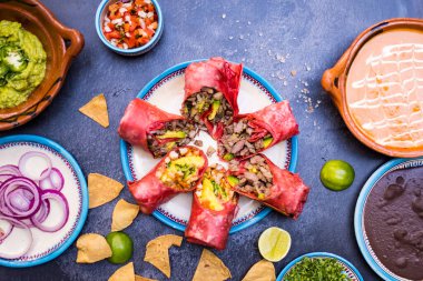 Lezzetli dürümler ve daha fazla Meksika baharatı ve karanlık yüzeyde yemekler.