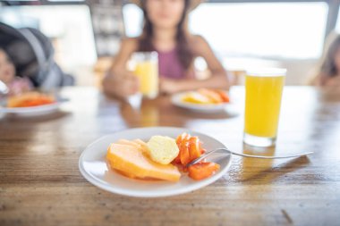 Lezzetli meyve dilimleri ve portakal suyu ahşap masada bulanık arka planda.